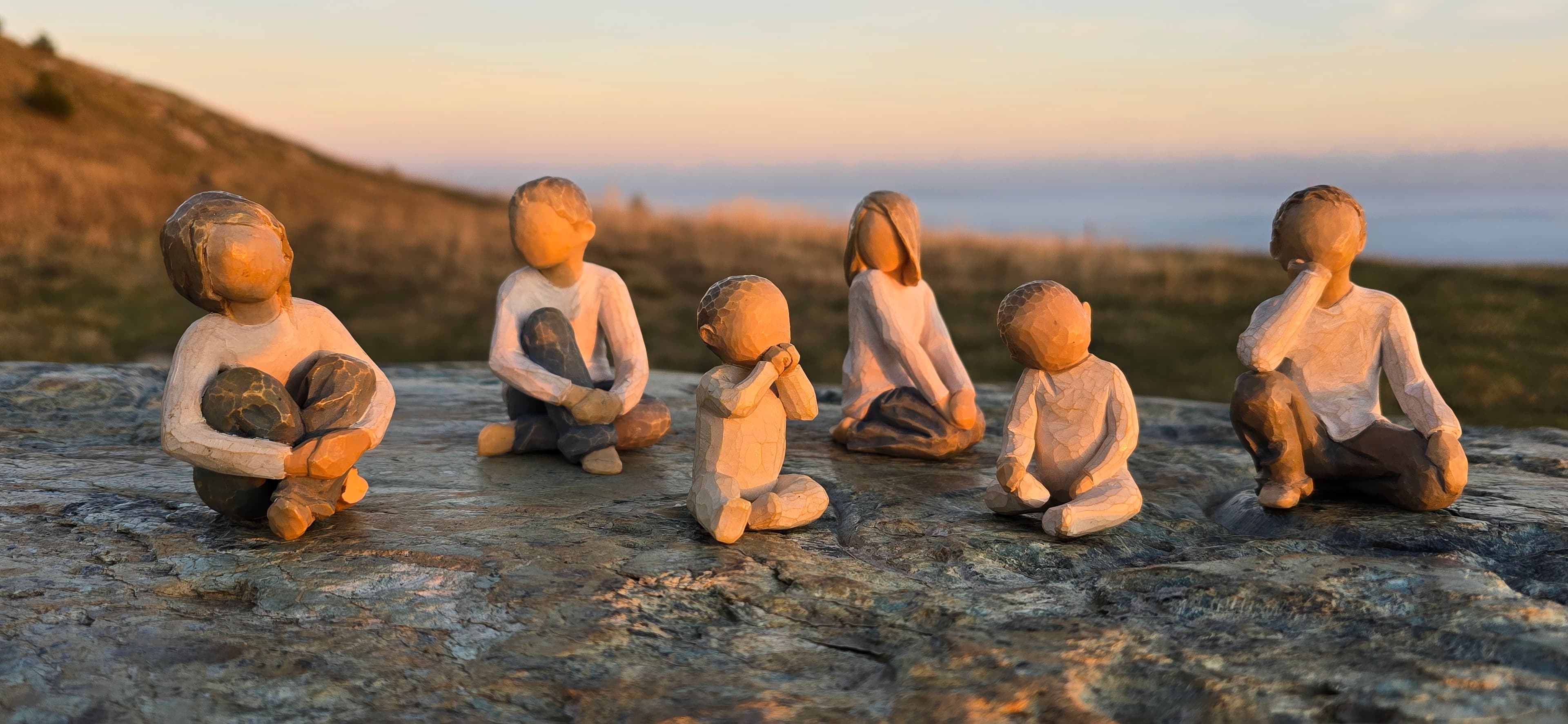 Figurines disposées dans un paysage naturel au coucher du soleil